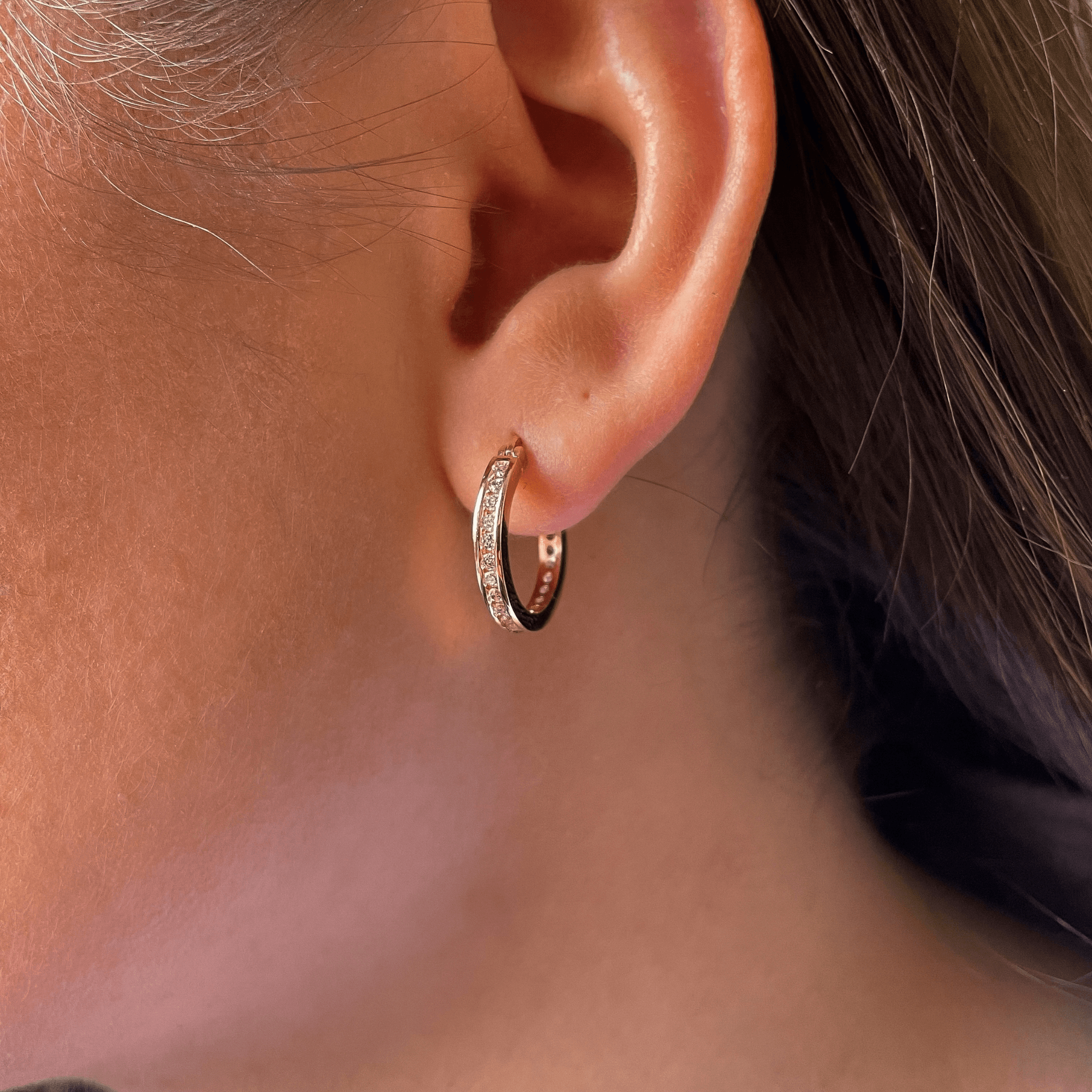 Boucle d’oreille créole en plaqué or sertie d’oxydes de zirconium blancs, portée à l’oreille, modèle Clarté.