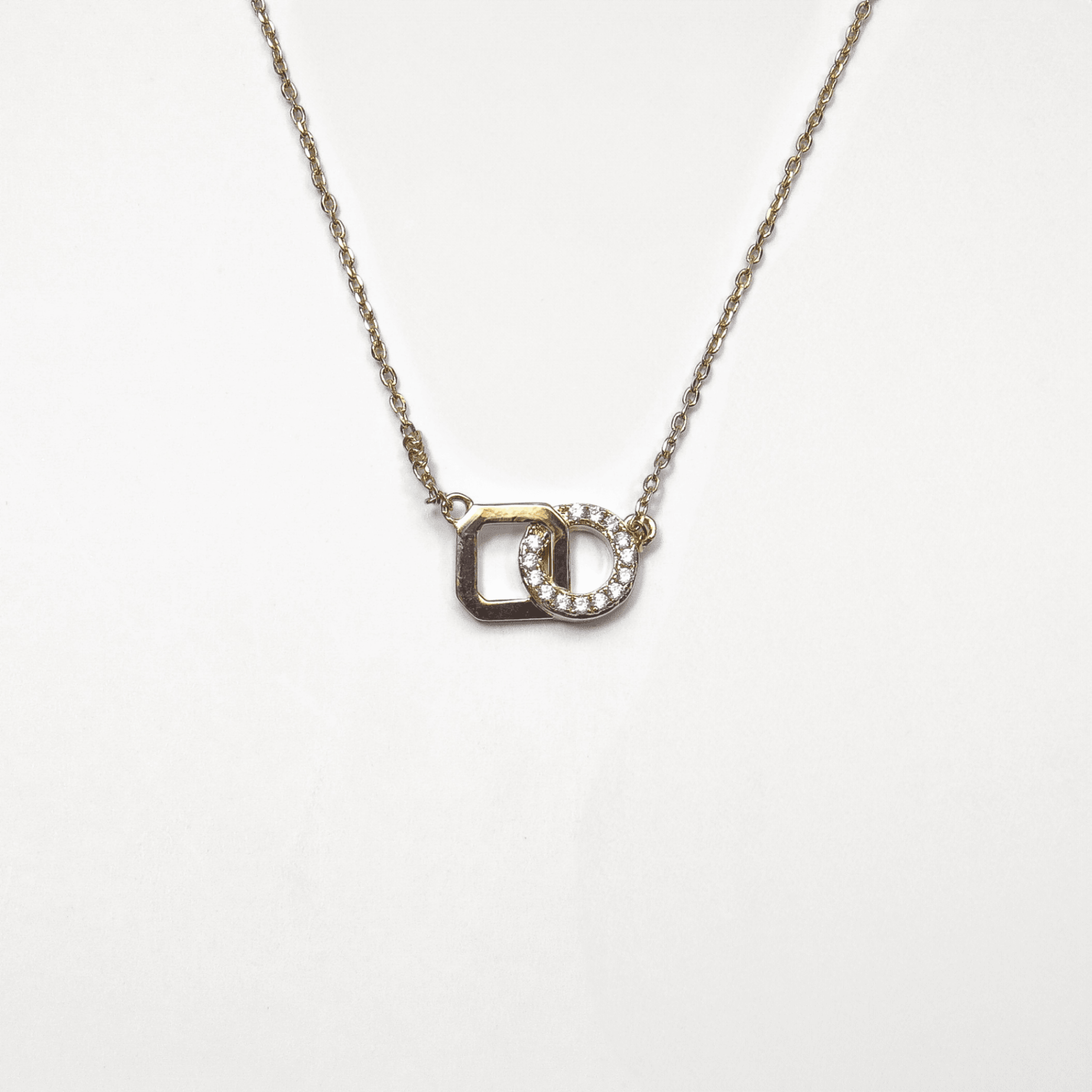 collier en plaqué or 18 carats avec deux anneaux entrelacés dont un pavé d’oxydes de zirconium blancs