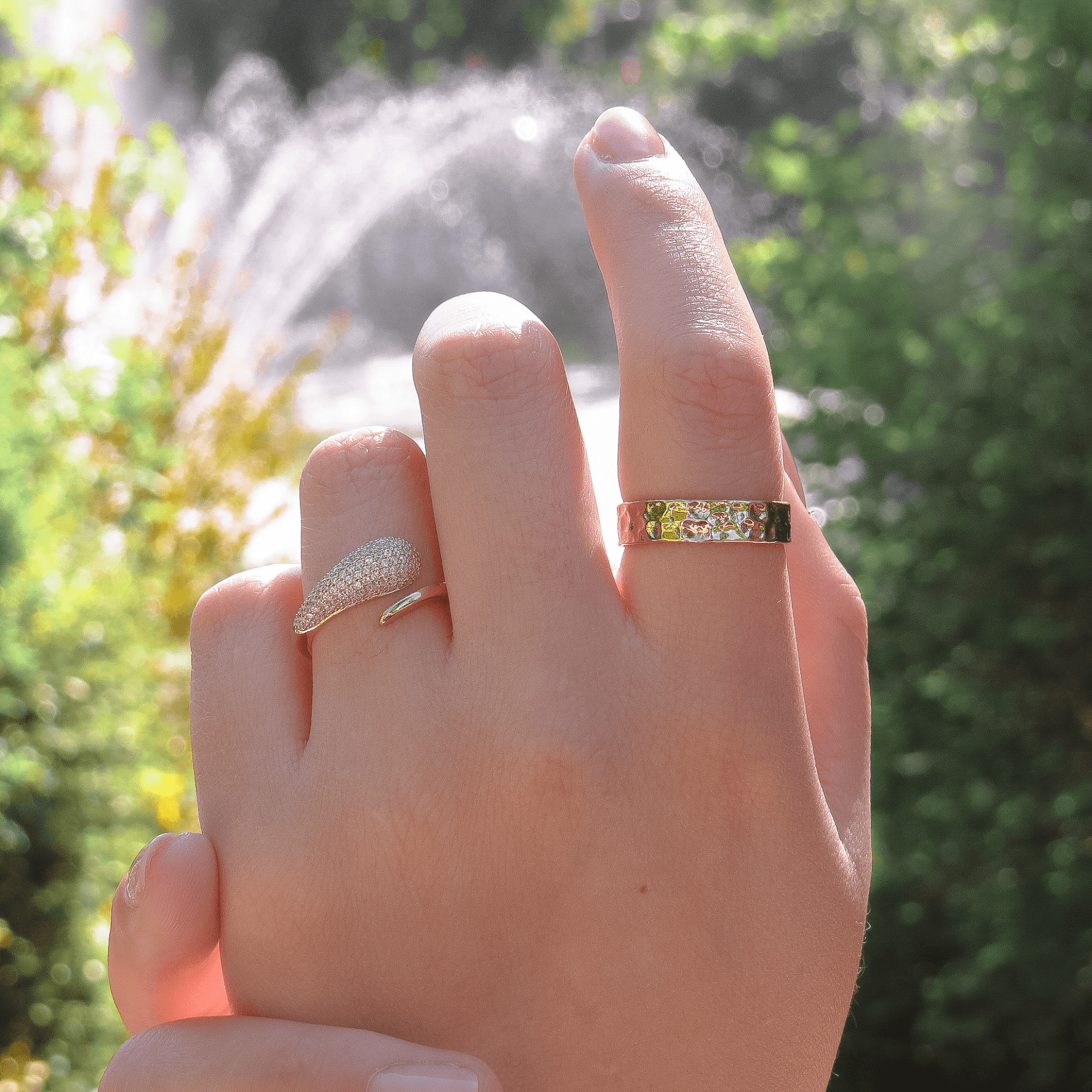 bague en plaqué or sertie d’oxydes de zirconium et bague martelée en plaqué or, portées sur une main féminine en extérieur