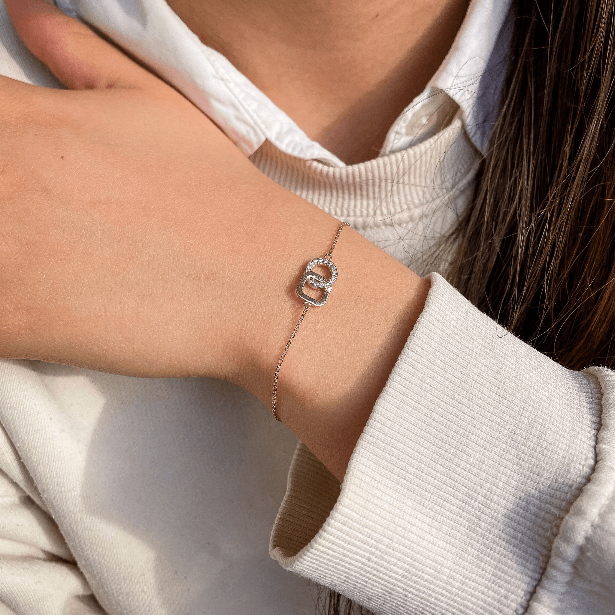 bracelet en plaqué or 18 carats avec deux anneaux entrelacés dont un pavé d’oxydes de zirconium blancs