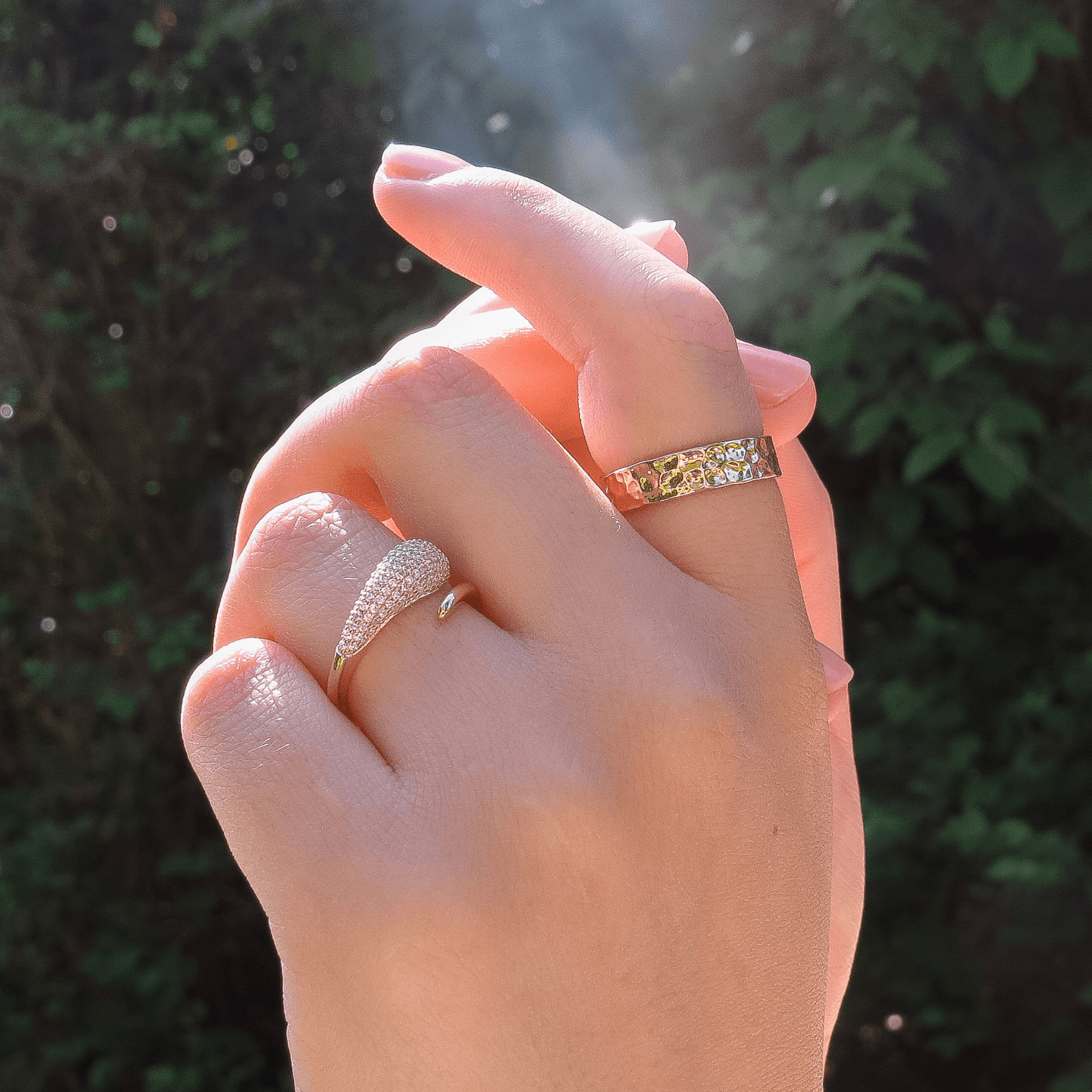 bague en plaqué or sertie d’oxydes de zirconium et bague martelée en plaqué or, portées sur une main féminine en extérieur