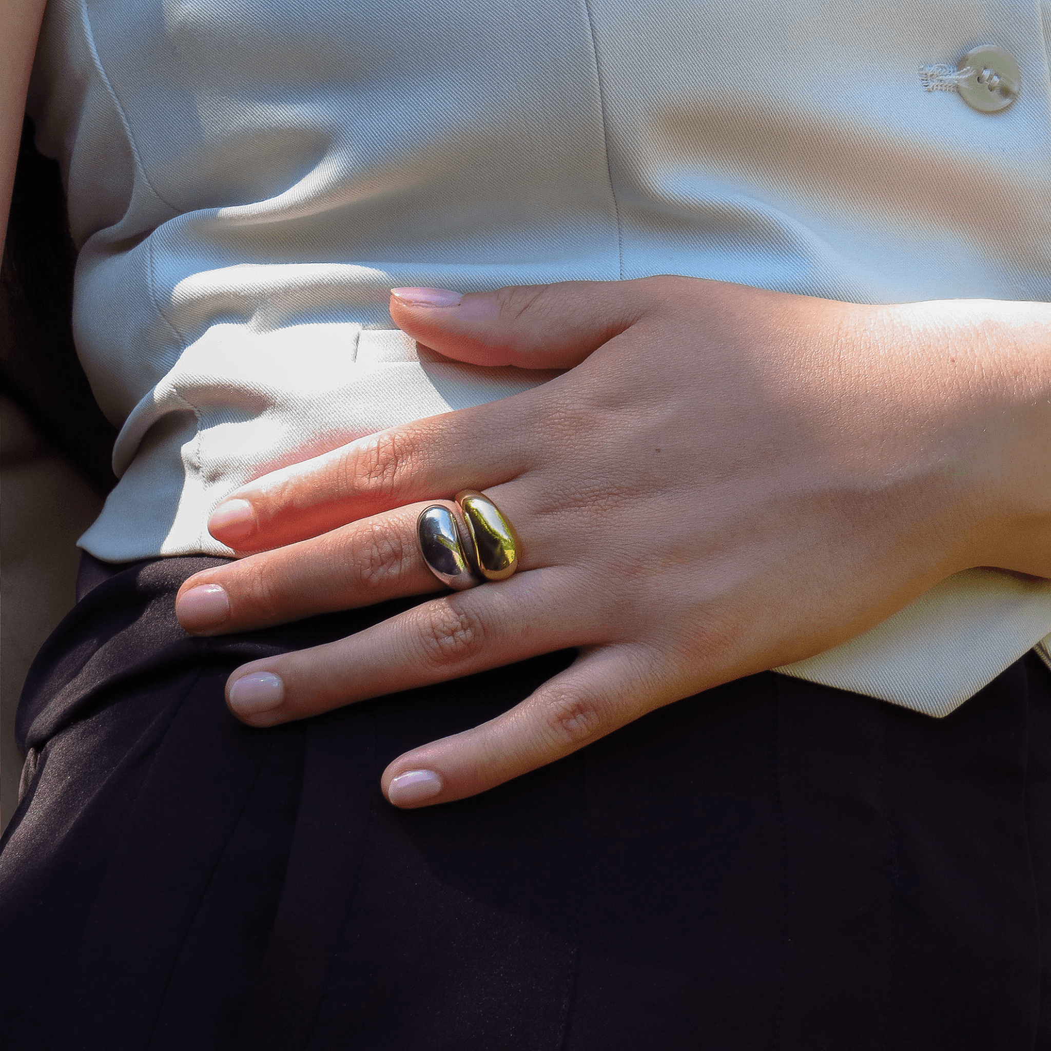 main portant une bague volumineuse bicolore en plaqué or et argent 925, design moderne sur fond de tenue habillée