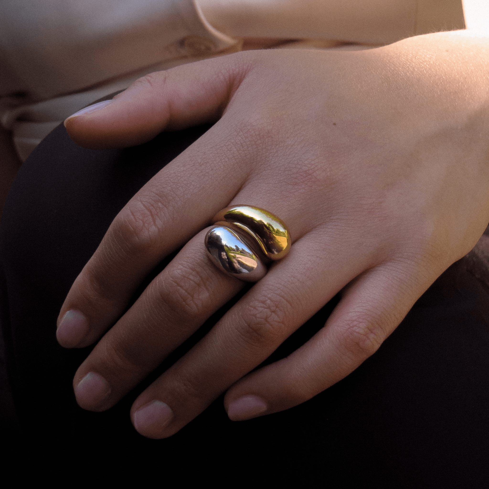 Bague au design massif mix en plaqué or et argent, porté sur fond de blouse blanche et pantalon noir