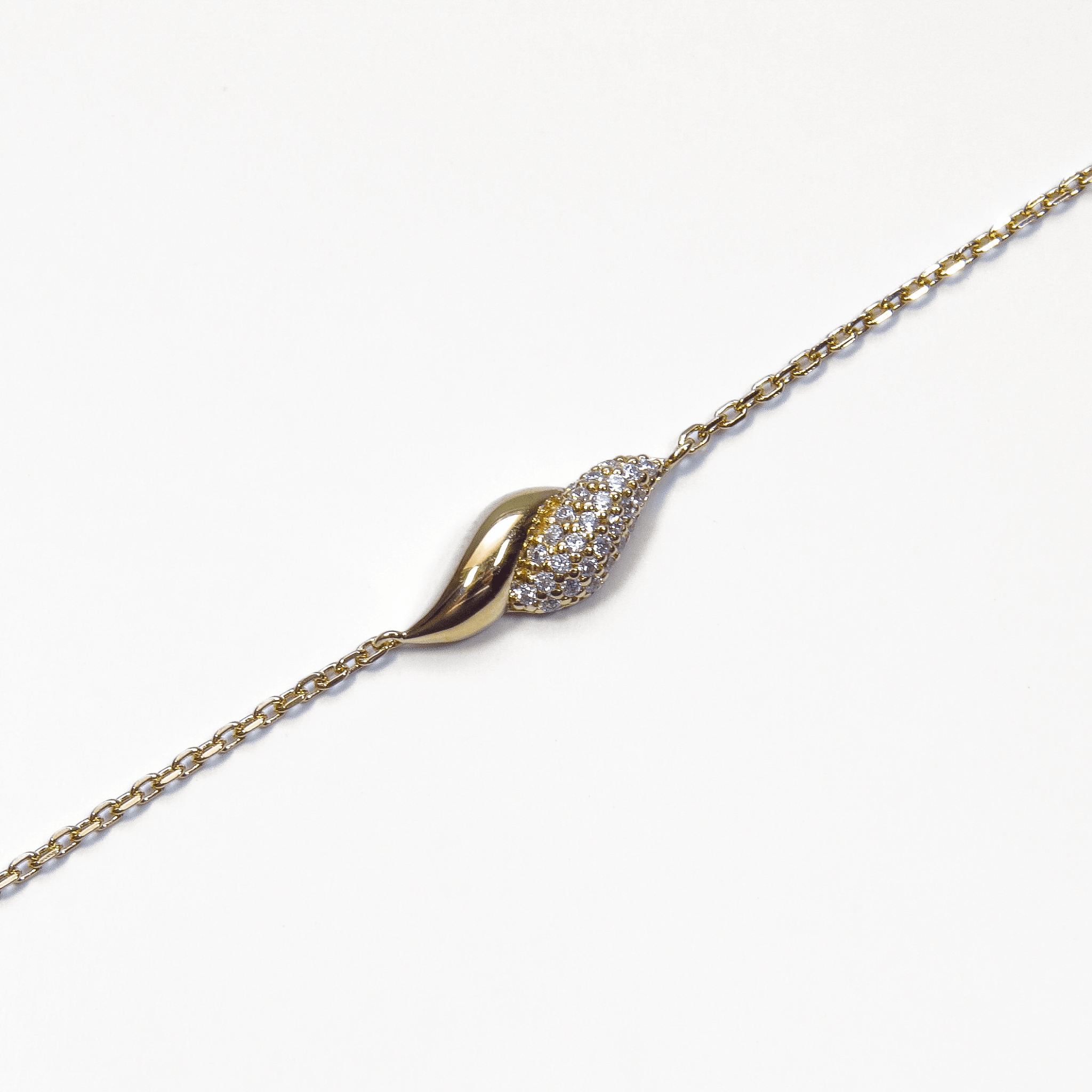 bracelet en plaqué or 18 carats avec motif courbé et oxydes de zirconium sur fond blanc